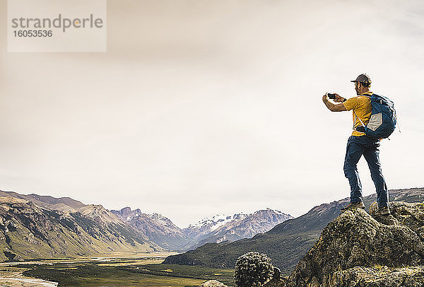 Älterer Mann fotografiert Berge mit Smartphone gegen den Himmel  Patagonien  Argentinien