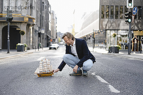 Geschäftsmann platziert Modellschiff auf einer Stadtstraße