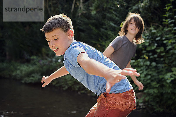 Jungen spielen im Bach im Wald