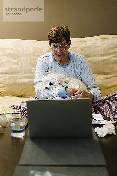 Kranke ältere Frau diskutiert über Videoanruf über Laptop zu Hause