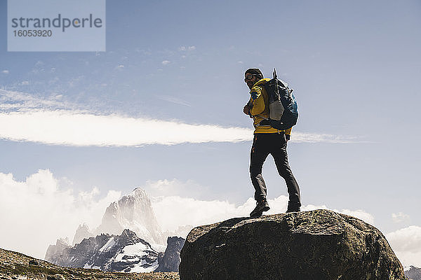 Männlicher Wanderer mit Rucksack auf einem Felsen stehend gegen den Himmel an einem sonnigen Tag  Patagonien  Argentinien