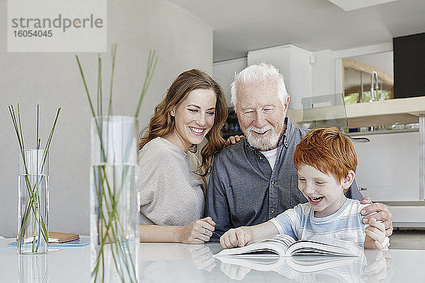 Glücklicher Großvater  Mutter und Sohn lesen ein Buch in einer Villa