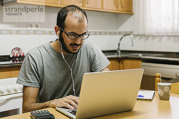Mann führt Videokonferenzen auf seinem Laptop durch  während er zu Hause arbeitet