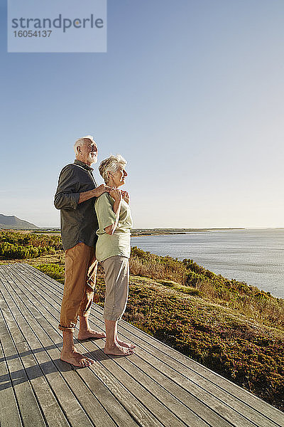 Älteres Paar genießt die Aussicht auf der Holzterrasse am Meer