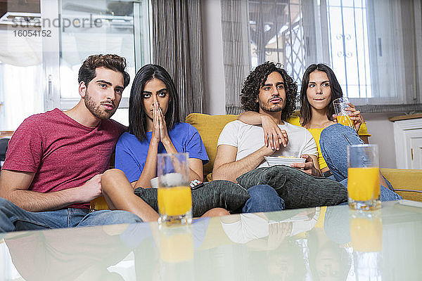 Junge multiethnische Freunde im Stress beim Fernsehen zu Hause