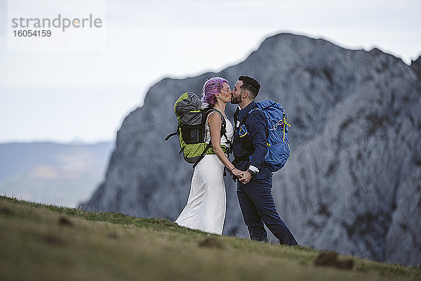 Küssendes Brautpaar mit Kletterrucksäcken auf dem Berg Urkiola  Spanien