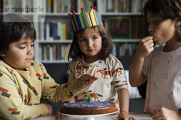 Porträt eines kleinen Mädchens  das seinen Geburtstag mit seinen älteren Brüdern zu Hause feiert