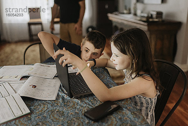 Geschwister lernen während der Ausgangssperre zu Hause am Laptop