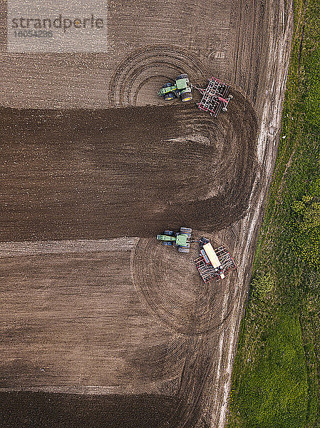 Russland  Oblast Moskau  Luftaufnahme von zwei Traktoren  die ein braunes Feld pflügen