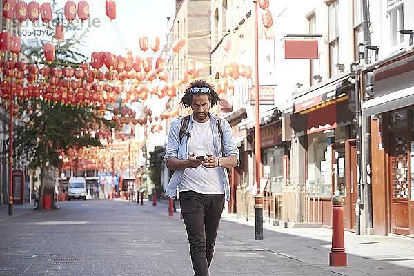 Junger Mann geht auf der Straße und schaut auf sein Smartphone  Chinatown  London  UK