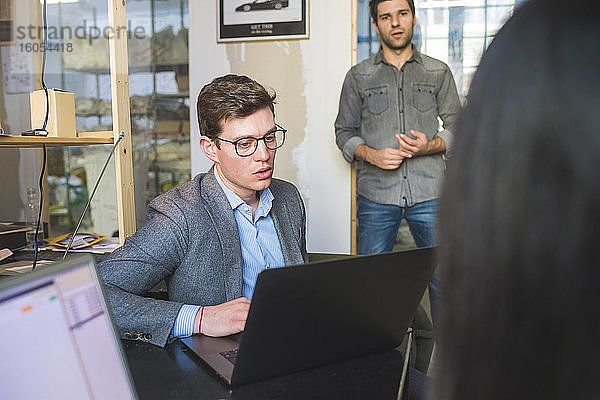 Drei Geschäftsleute mit Laptop bei einem Treffen im Büro