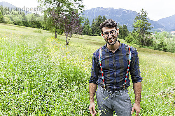 Porträt eines lächelnden jungen Mannes  der auf einer Wiese steht  Reichenwies  Oberammergau  Deutschland