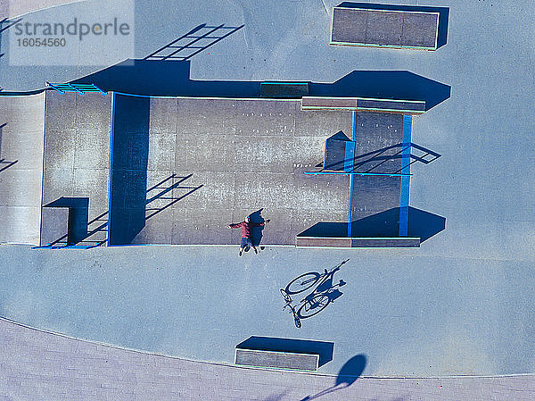 Mann liegt auf Betonrampe in Skatepark  Luftaufnahme