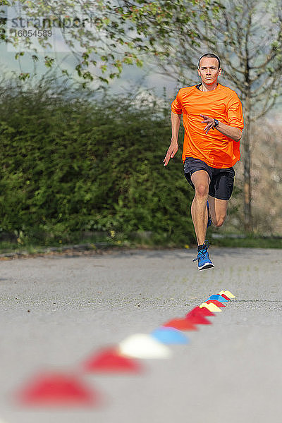 Junger männlicher Sportler  der an einem sonnigen Tag auf einem Fußweg läuft