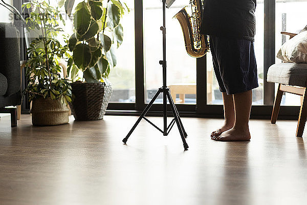 Crop-Ansicht eines Jungen  der zu Hause Saxophon spielen übt