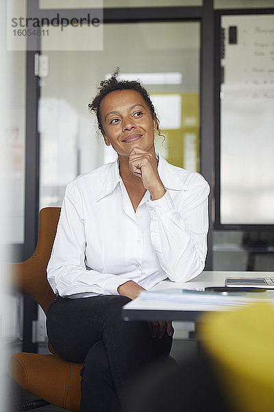 Porträt einer lächelnden Geschäftsfrau  die am Schreibtisch im Büro sitzt