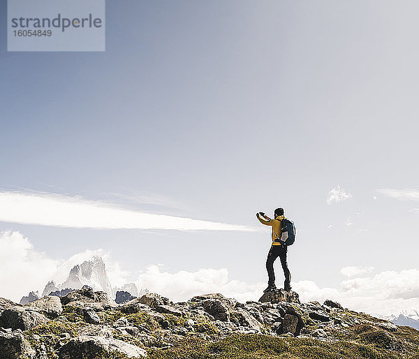 Mann fotografiert auf einem Berg stehend gegen den Himmel an einem sonnigen Tag  Patagonien  Argentinien