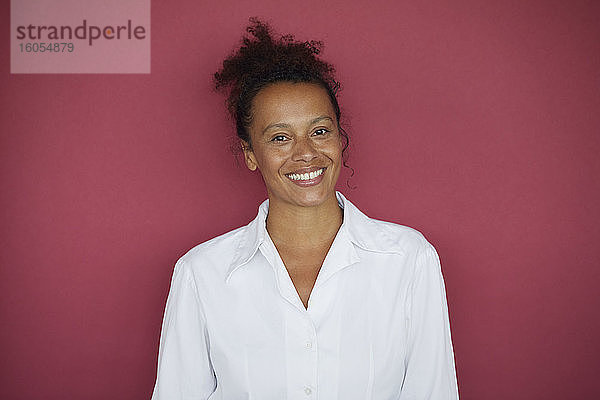Porträt einer lächelnden Geschäftsfrau vor rotem Hintergrund