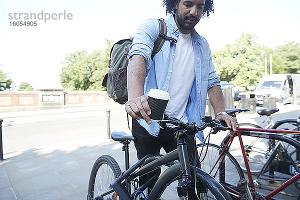 Junger Mann parkt Fahrrad vor dem Bahnhof
