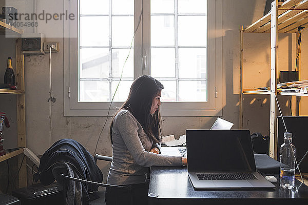 Frau mit Laptop am Schreibtisch im Büro