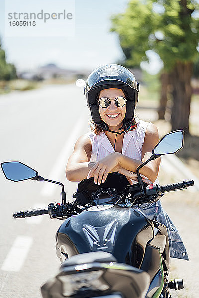 Motorradfahrerin mit Sonnenbrille auf dem Motorrad sitzend