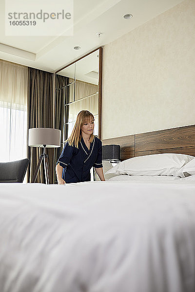 Zimmermädchen macht Bett im Hotelzimmer