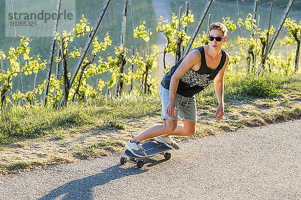 Hübsche junge Frau  die an einem sonnigen Tag auf der Straße Skateboard fährt