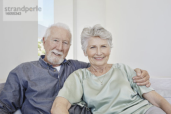 Porträt eines lächelnden älteren Paares  das auf einer Couch in einer Villa sitzt