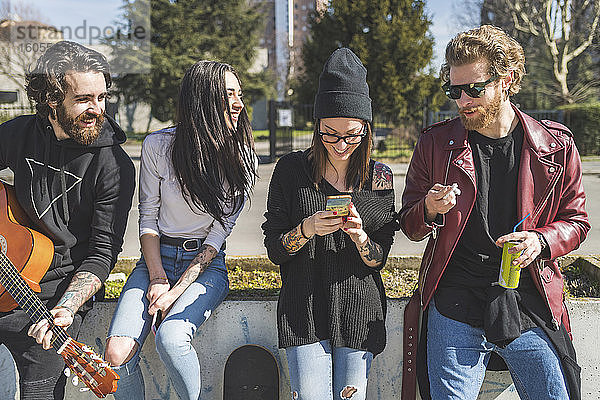Mittlere erwachsene Frau benutzt ein Smartphone  während sie mit Freunden in der Stadt steht