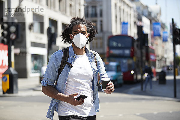 Porträt eines jungen Mannes mit Schutzmaske beim Überqueren der Straße  London  UK