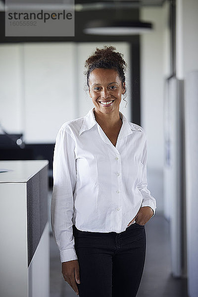 Porträt einer lächelnden Geschäftsfrau  die in einem modernen Büro steht