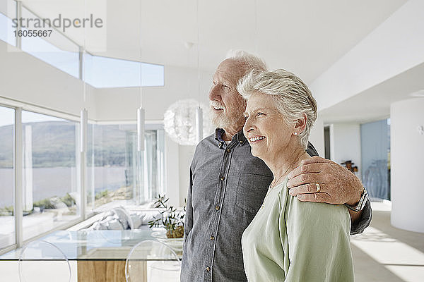 Glückliches älteres Paar in luxuriösem Strandhaus mit Blick aus dem Fenster