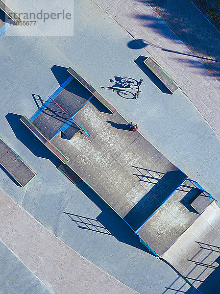 Mann sitzt auf Betonrampe in Skatepark  Luftaufnahme