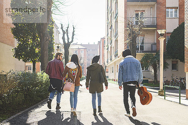 Freunde gehen auf der Straße inmitten von Gebäuden in der Stadt an einem sonnigen Tag