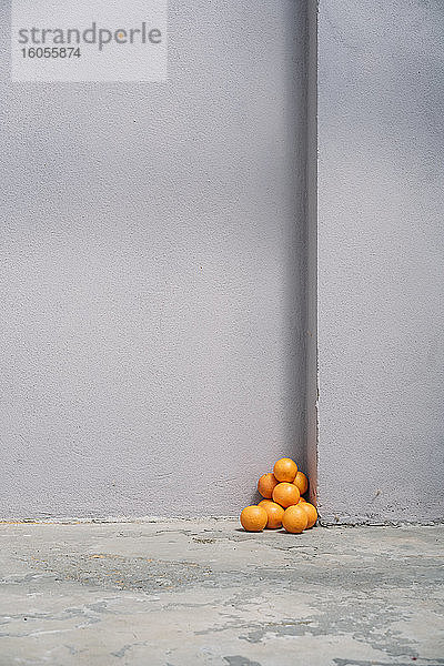 Stapel von Orangen in der Ecke einer grauen Wand