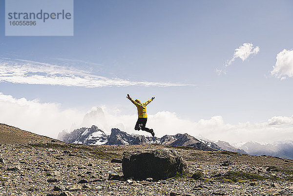 Unbekümmerter reifer Mann  der auf einem Felsen gegen den Himmel springt  Patagonien  Argentinien