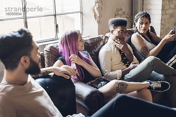 Gruppe von Freunden sitzt auf einem Sofa in einem Loft