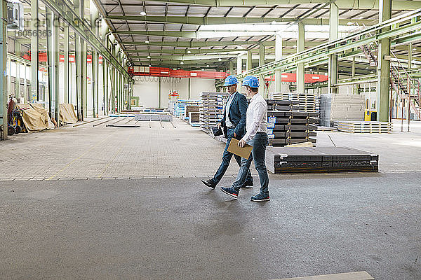 Zwei Geschäftsleute bei einem Treffen und einem Spaziergang in einer Fabrik