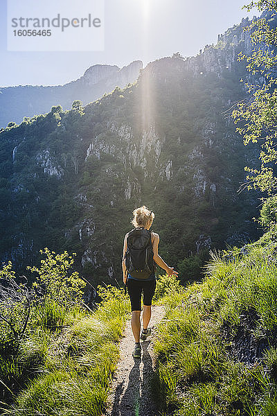 Frau mit Rucksack beim Wandern auf einem Bergpfad an einem sonnigen Tag  Lecco  Italien