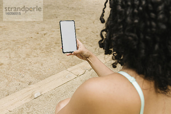 Sportliche junge Frau benutzt Smartphone im Park