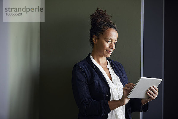 Porträt einer Geschäftsfrau  die ein digitales Tablet im Büro benutzt