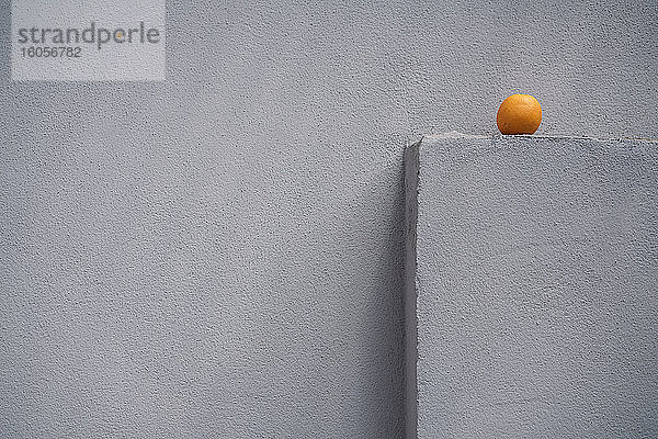 Einzelne Orange auf einem grauen Mauervorsprung
