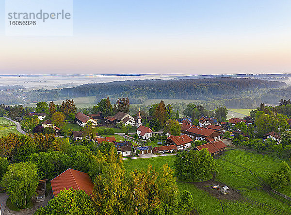 Deutschland  Bayern  Walchstadt  Drohnenansicht eines Dorfes auf dem Land bei nebligem Sonnenaufgang