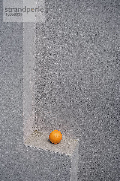 Einzelne Orange auf einem grauen Mauervorsprung