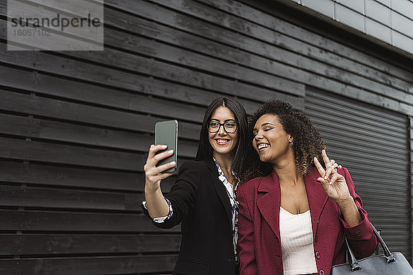 Schöne Geschäftsfrau nimmt Selfie mit weiblichen Kollegen in der Stadt