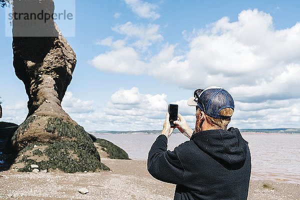 Mann fotografiert eine Felsformation im Hopewell Rocks Park  New Brunswick  Kanada