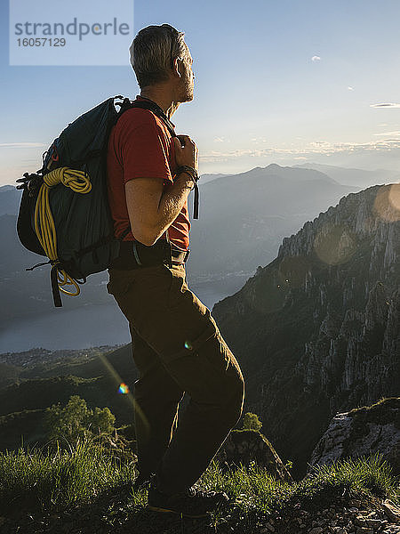 Männlicher Wanderer  der während des Sonnenuntergangs auf einem Berg stehend die Aussicht betrachtet  Orobie  Lecco  Italien