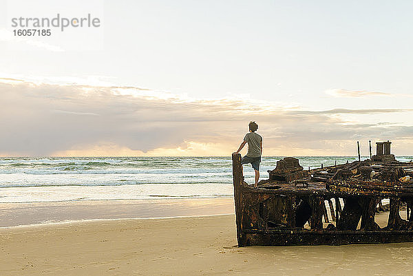 Mann schaut auf das Meer  während er auf dem Maheno-Schiffswrack auf Fraser Island  Queensland  Australien steht