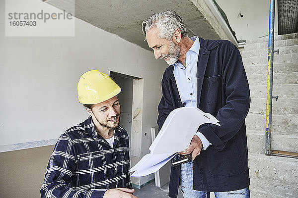Architekt und Arbeiter besprechen einen Bauplan auf einer Baustelle