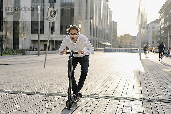 Geschäftsmann fährt Kick-Scooter in der Stadt